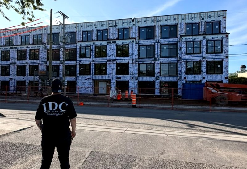 Installateur d'IDC devant un immeuble multilogements neuf à Montréal, avant l'installation des cuisines en série
